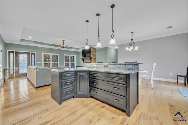 kitchen with baseboards, visible vents, a raised ceiling, crown molding, and light wood-style floors