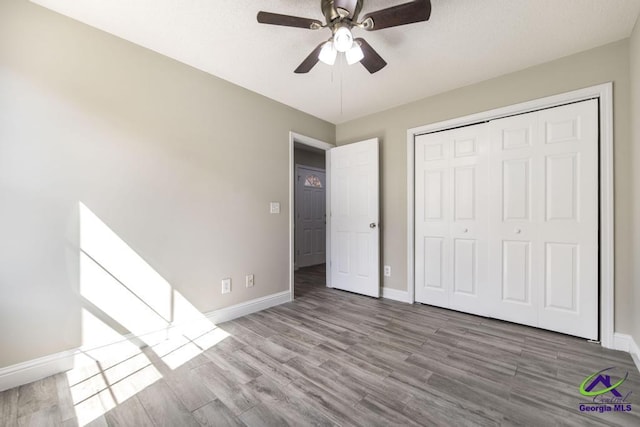 unfurnished bedroom with a closet, ceiling fan, baseboards, and wood finished floors