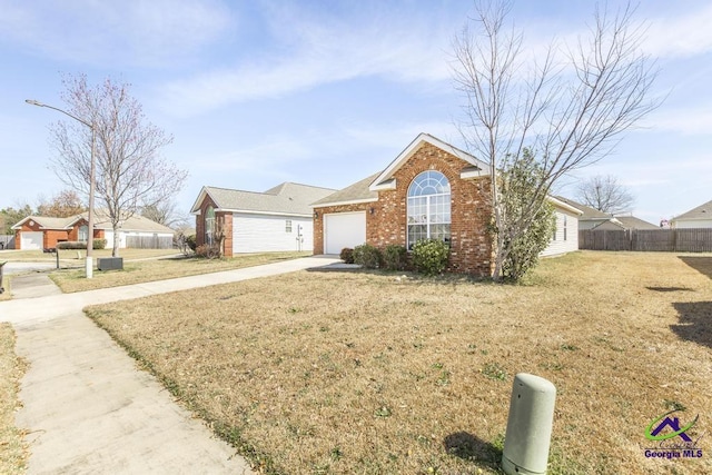 view of front facade with a garage, brick siding, fence, driveway, and a front yard