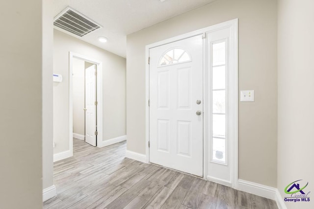 foyer entrance with baseboards, visible vents, and light wood finished floors