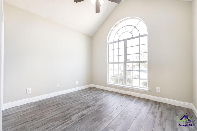 unfurnished room with vaulted ceiling, ceiling fan, wood finished floors, and baseboards