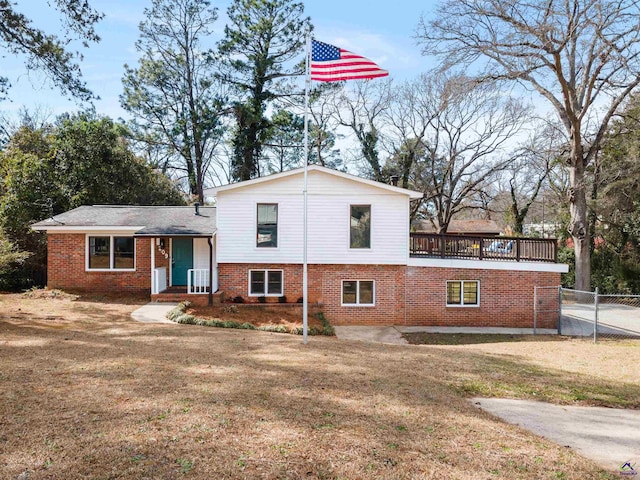 view of front of house with brick siding, a front yard, and fence