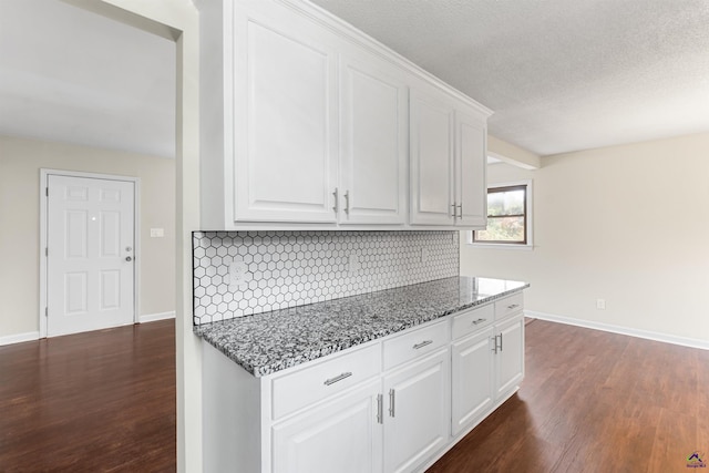 kitchen with stone countertops, dark wood-type flooring, baseboards, white cabinets, and backsplash