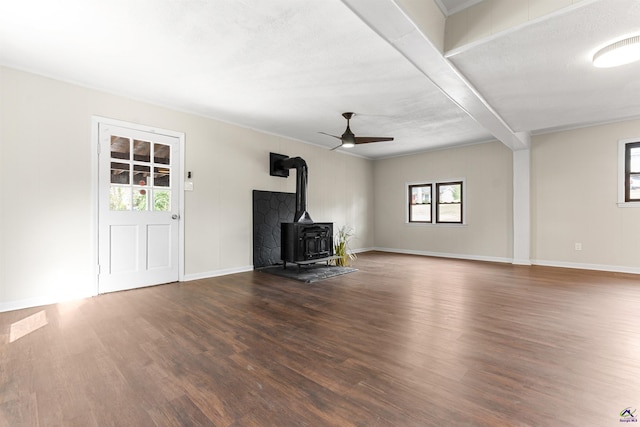 unfurnished living room featuring a wood stove, baseboards, a ceiling fan, and wood finished floors