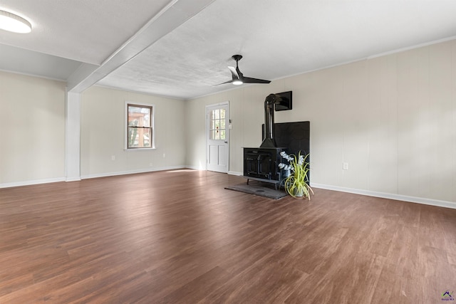 unfurnished living room with a wood stove, baseboards, a ceiling fan, and wood finished floors