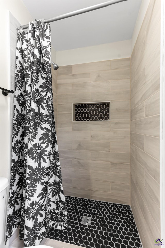 full bath featuring a tile shower and toilet