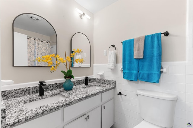 full bathroom with wainscoting, a sink, and tile walls