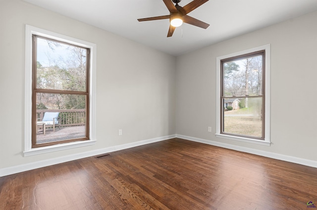 unfurnished room featuring visible vents, dark wood finished floors, baseboards, and ceiling fan