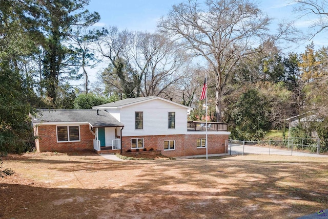 tri-level home with a gate, fence, and brick siding