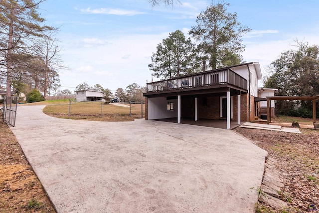 exterior space with concrete driveway, brick siding, fence, and a wooden deck