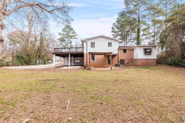 rear view of property featuring brick siding, a patio, a lawn, a carport, and a wooden deck