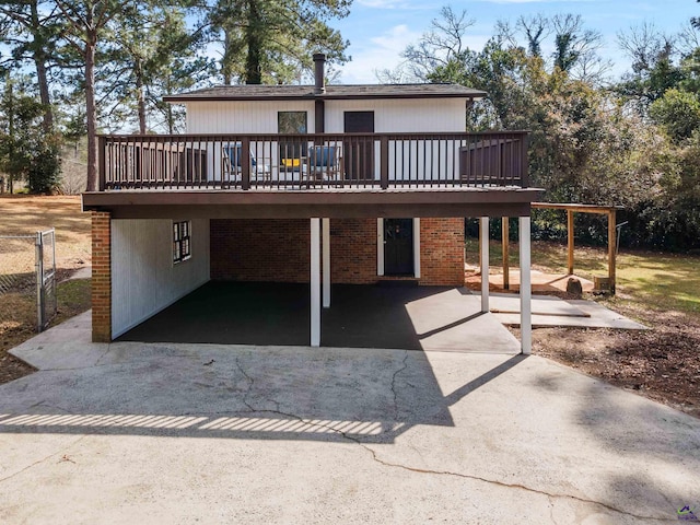 view of front of house with an attached carport, brick siding, driveway, a wooden deck, and a patio area