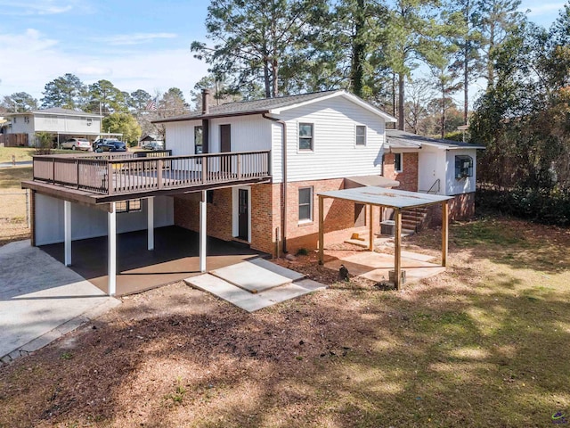 rear view of house featuring driveway, a patio area, a deck, and brick siding