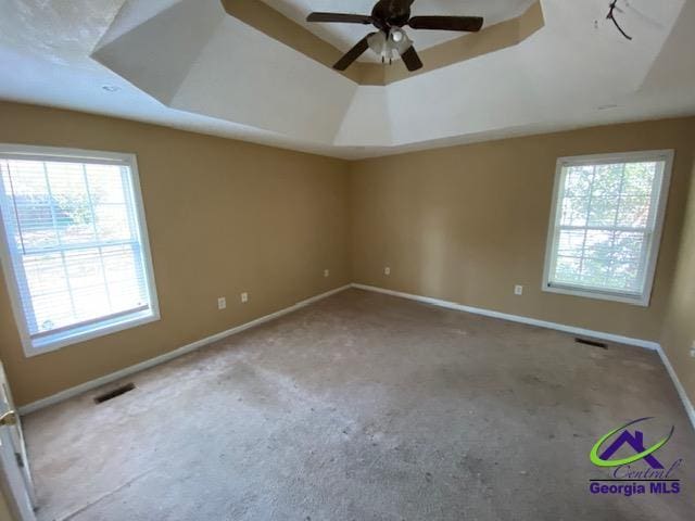 empty room featuring ceiling fan, baseboards, visible vents, and a raised ceiling