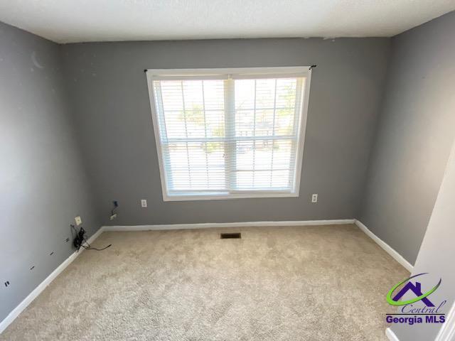 empty room with light colored carpet, visible vents, and baseboards