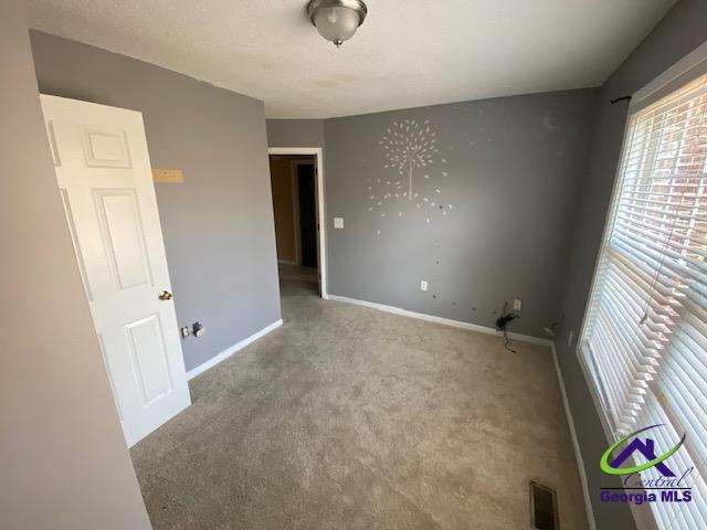 empty room featuring carpet floors, baseboards, and visible vents