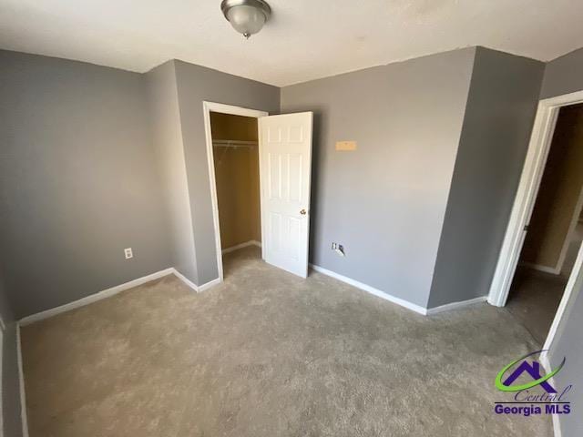 unfurnished bedroom with carpet, a closet, and baseboards