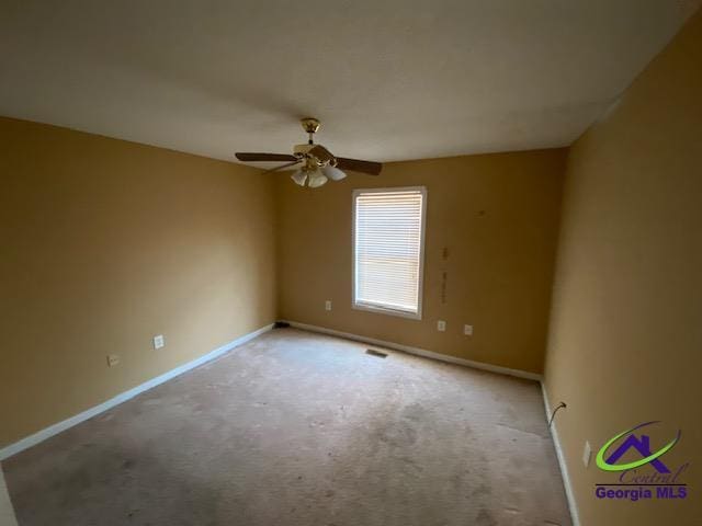 carpeted empty room featuring a ceiling fan, visible vents, and baseboards