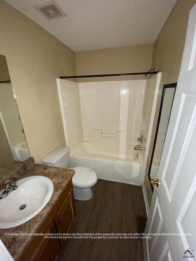 full bath featuring visible vents, toilet, wood finished floors, vanity, and washtub / shower combination