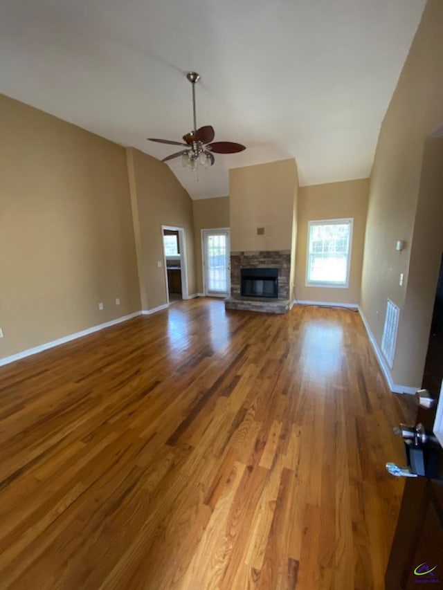 unfurnished living room featuring light wood-type flooring, a stone fireplace, and baseboards