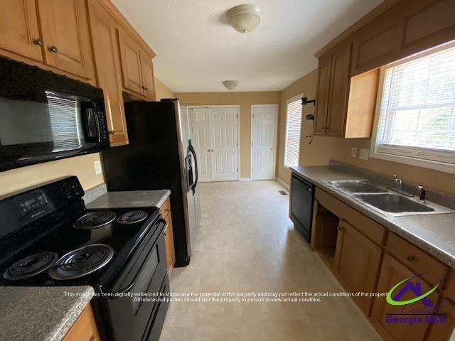 kitchen featuring black appliances, baseboards, and a sink