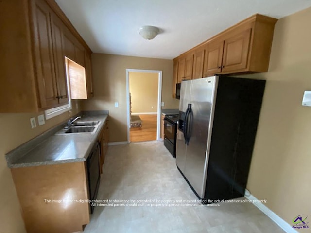 kitchen featuring a sink, baseboards, stainless steel refrigerator with ice dispenser, black electric range oven, and light floors