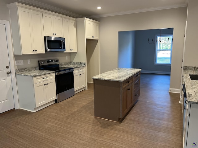 kitchen with appliances with stainless steel finishes, white cabinetry, and ornamental molding