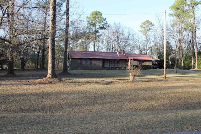 view of front of home featuring a tiled roof, a chimney, and a front yard