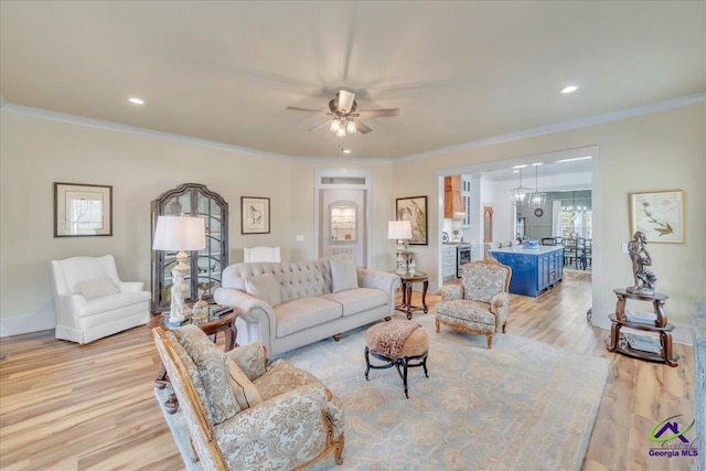 living room with ornamental molding, light wood-type flooring, recessed lighting, and ceiling fan with notable chandelier