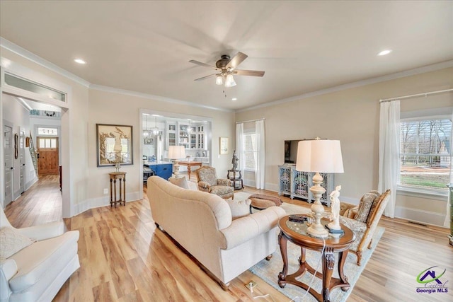 living room featuring light wood finished floors, ceiling fan, and ornamental molding