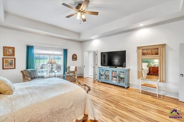 bedroom with a tray ceiling, recessed lighting, light wood-style floors, ceiling fan, and baseboards