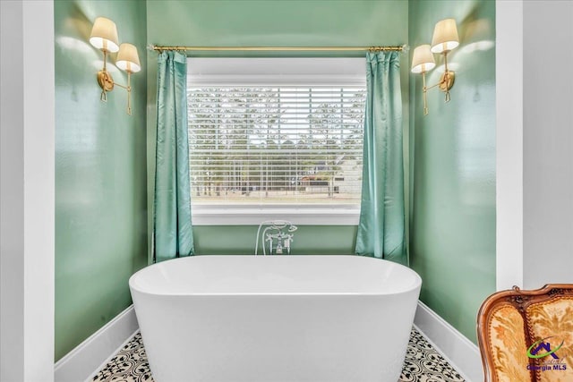 bathroom with a soaking tub, tile patterned floors, and baseboards