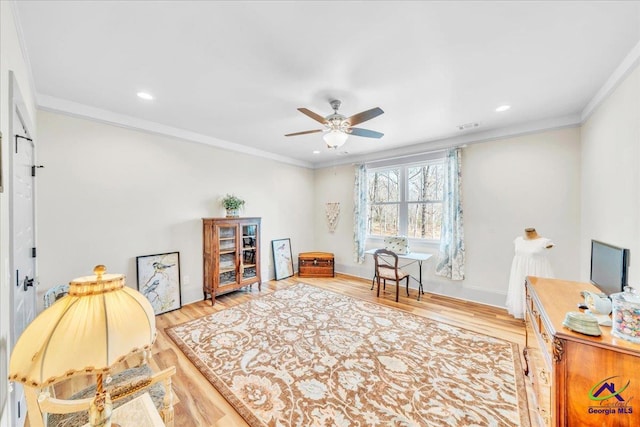 interior space featuring baseboards, visible vents, a ceiling fan, ornamental molding, and wood finished floors