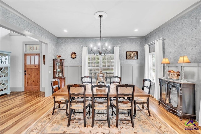 dining room with wood finished floors, a wainscoted wall, an inviting chandelier, and wallpapered walls