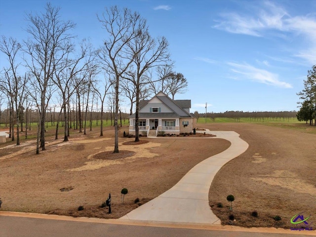 view of front facade with a porch, a rural view, and driveway