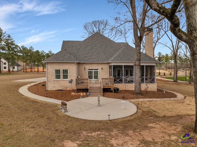 back of house featuring roof with shingles, brick siding, a chimney, and a wooden deck