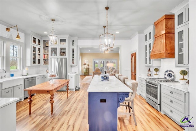 kitchen featuring a breakfast bar area, stainless steel appliances, a sink, a center island, and light wood finished floors