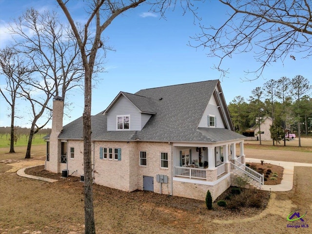 rear view of property with a porch, a chimney, a shingled roof, and driveway