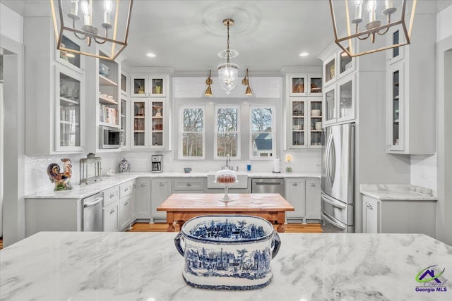 kitchen featuring stainless steel appliances, decorative backsplash, white cabinets, and light stone countertops