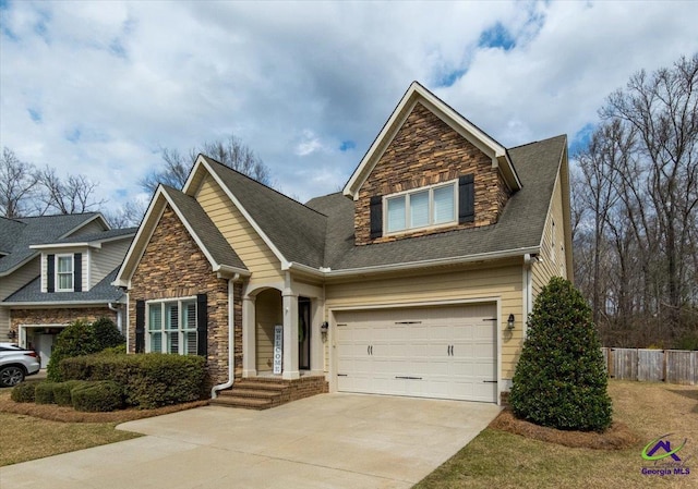 view of front of house featuring driveway, stone siding, a shingled roof, and fence