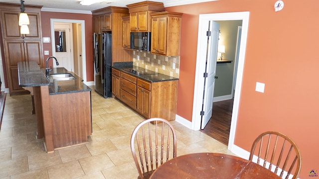 kitchen featuring a sink, ornamental molding, brown cabinets, decorative backsplash, and black appliances