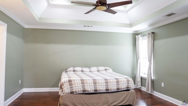 bedroom with a tray ceiling, visible vents, and wood finished floors