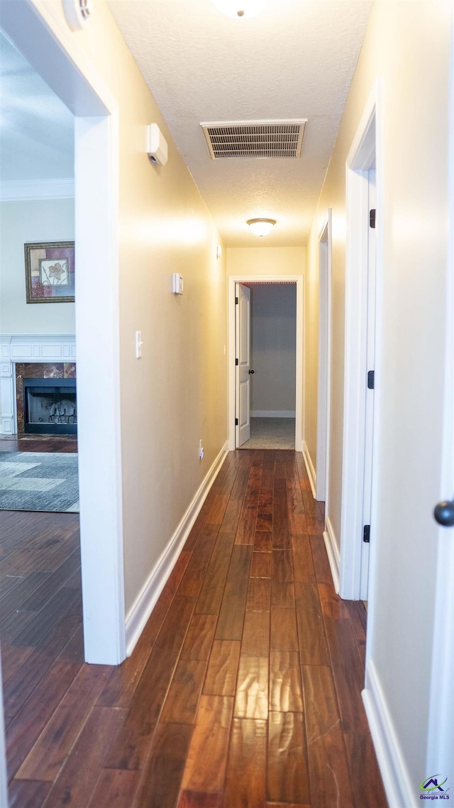 hallway with wood finished floors, visible vents, and baseboards