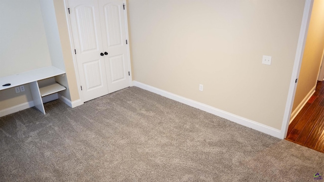 unfurnished bedroom with baseboards, dark colored carpet, and a closet