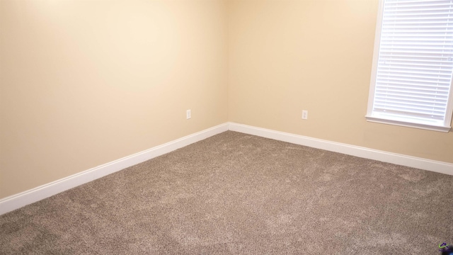 empty room featuring baseboards and dark colored carpet