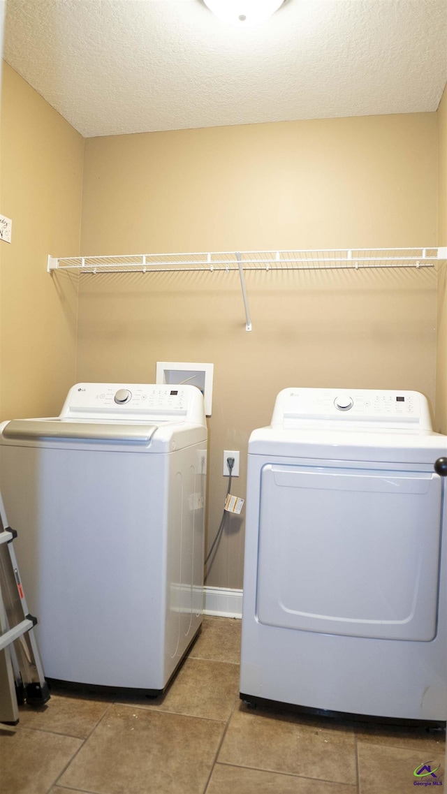 clothes washing area featuring laundry area, light tile patterned floors, and washing machine and clothes dryer