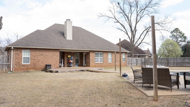 rear view of property with a patio area, a shingled roof, fence, and brick siding