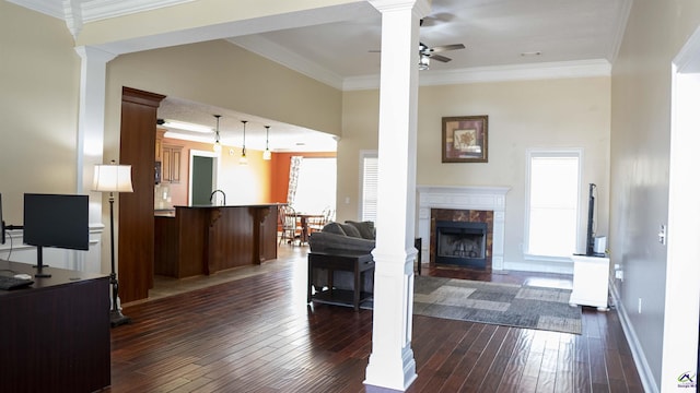 living area featuring crown molding, dark wood-style flooring, a high end fireplace, and ornate columns