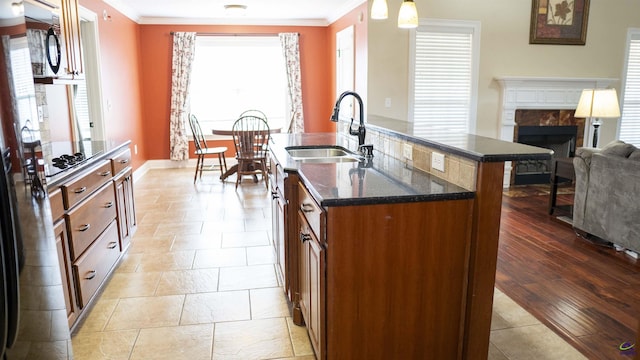 kitchen featuring dark stone counters, a fireplace, a sink, and crown molding