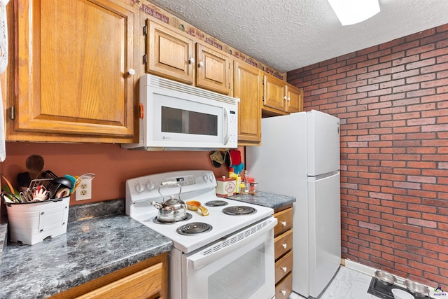 kitchen featuring marble finish floor, dark countertops, a textured ceiling, brick wall, and white appliances